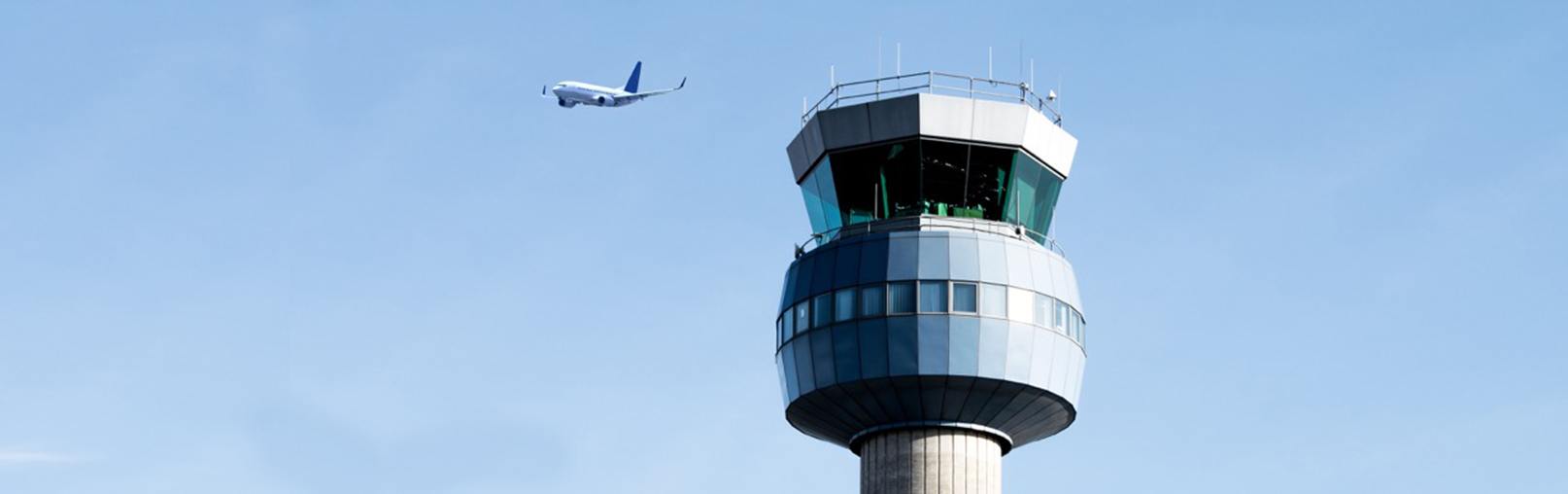 silouette of departing aircraft by control tower